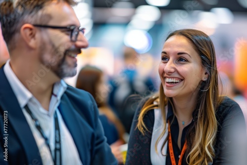the bustling energy of a trade show as a cheerful businesswoman engages in conversation  radiating happiness in front of a well-lit exhibition stand.