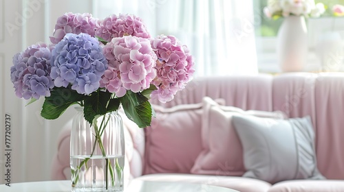 Bouquet of pastel hydrangeas in glass vase Flowers in a vase at home beautiful bouquet of hydrangeas is in a vase on a table near a pink sofa in a white living room