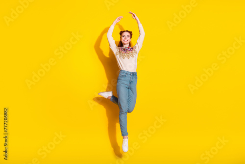 Photo portrait of pretty young woman jump dance ballet raise hands dressed stylish knitted warm outfit isolated on yellow color background photo