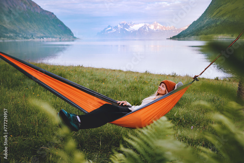 Traveler woman chilling in hammock travel lifestyle summer vacations trip in Norway girl relaxing outdoor enjoying fjord and mountains view harmony with nature eco tourism © EVERST