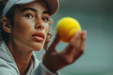 An intense portrait of a tennis player with freckles, holding a yellow tennis ball, and focused