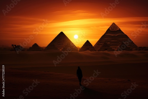 Silhouette of a person against the rising sun and the pyramids.