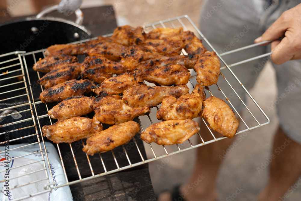 A man on a picnic holds a net with appetizing ready-to-grill meat and lays it out with tongs A man on a picnic holds a net with appetizing ready-to-grill meat and lays it out with tongs