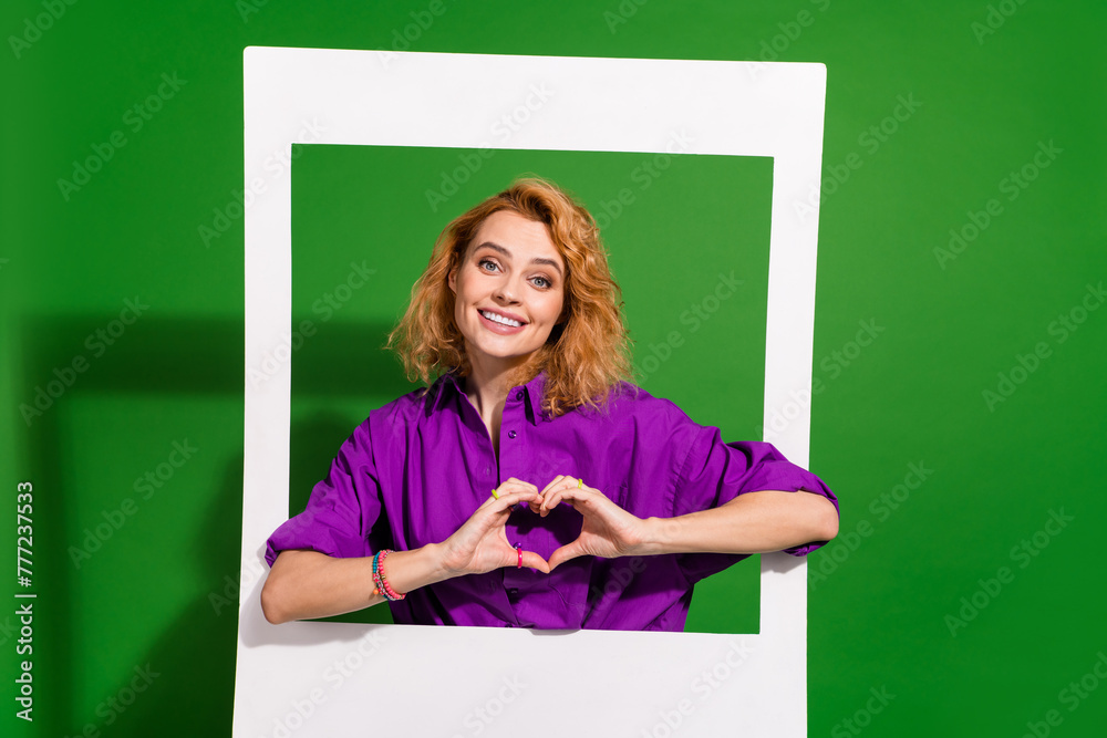 Photo portrait of lovely lady hold instant photo frame show heart gesture dressed stylish violet clothes isolated on green color background Photo portrait of lovely lady hold instant photo frame show heart gesture dressed stylish violet clothes isolated on green color background