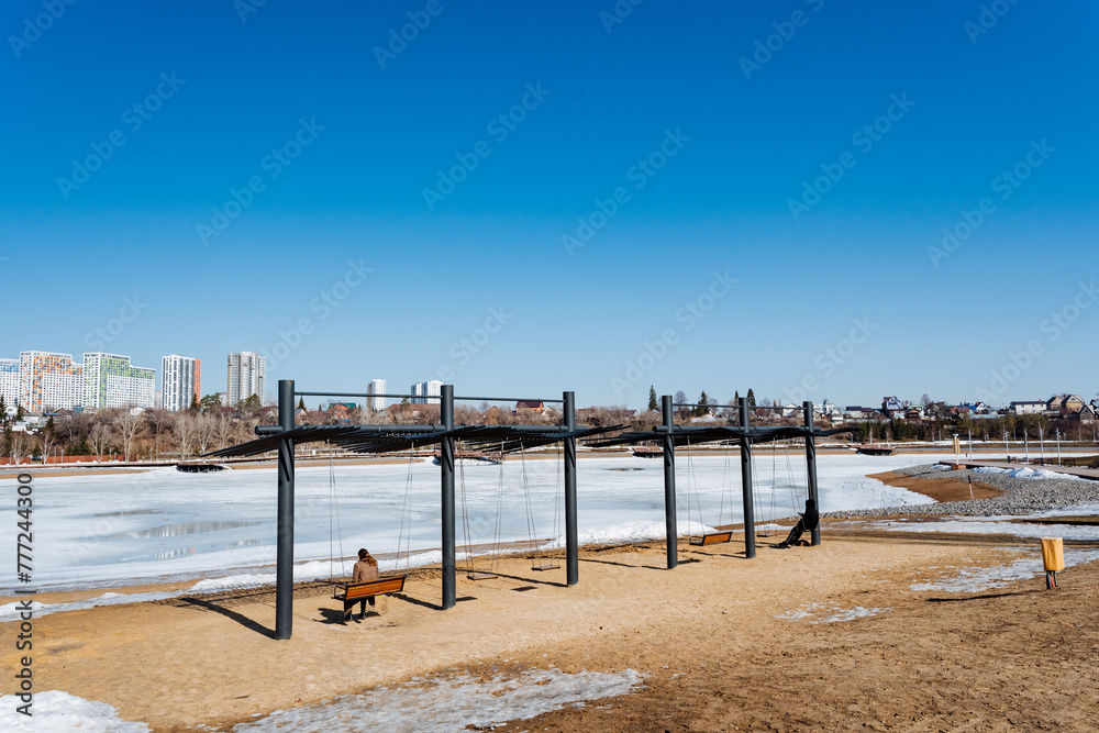 a person is sitting on a bench in a park near a frozen lake