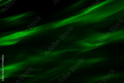 Defocused abstract green background of speed camera movement over glowing lights. A pattern of flashes of light similar to the northern lights