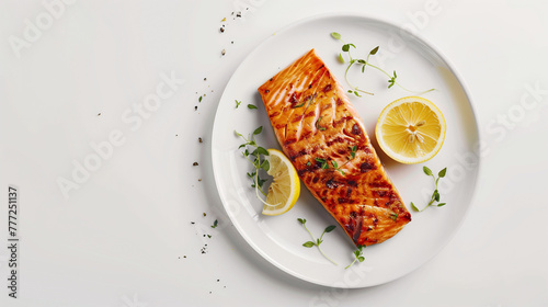 Grilled salmon fillets on a white plate with lemon slices and herbs. Studio photography with high contrast lighting. Healthy eating and seafood concept. Flat lay composition with copy space. photo