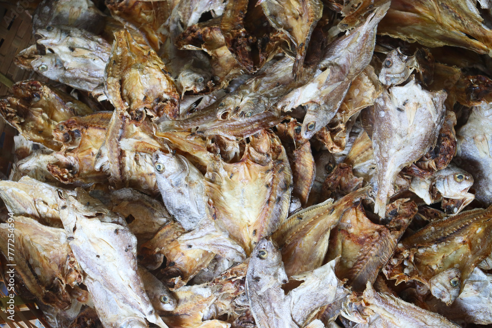 close up of dried fish gathered for sale with flies over it.