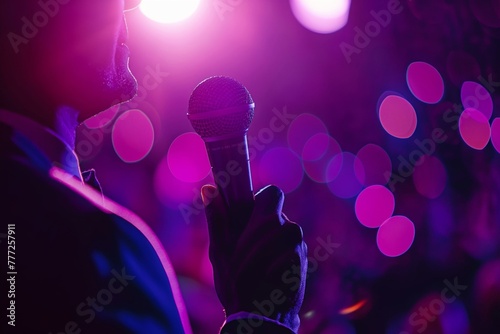 A man in a business suit holds a microphone, addressing the audience. The background is an unfocused crowd of listeners in the hall. Education, presentation, conference © BajimBa
