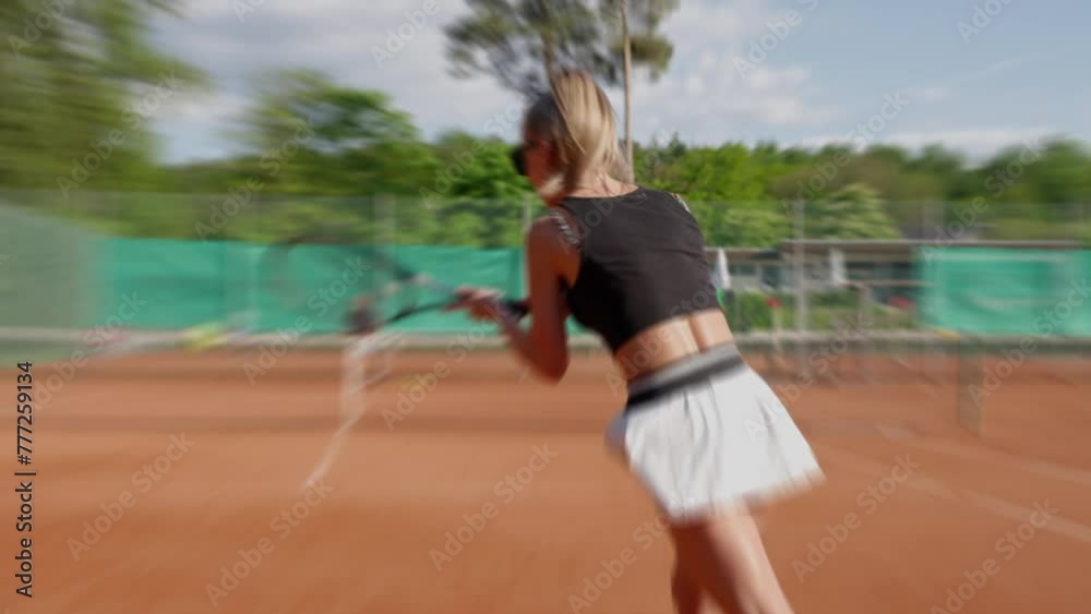 A woman moves along a clay tennis court, holding a tennis racket in her hand. Her thumb wraps around the handle as she prepares to have fun playing tennis. Slow motion A woman moves along a clay tennis court, holding a tennis racket in her hand. Her thumb wraps around the handle as she prepares to have fun playing tennis. Slow motion