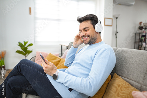 Man with wireless headphones listening to music in the living room