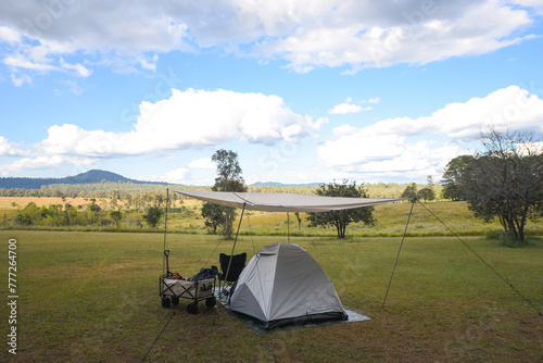 The tent is located on the grass with a mountain view and the sky is bright