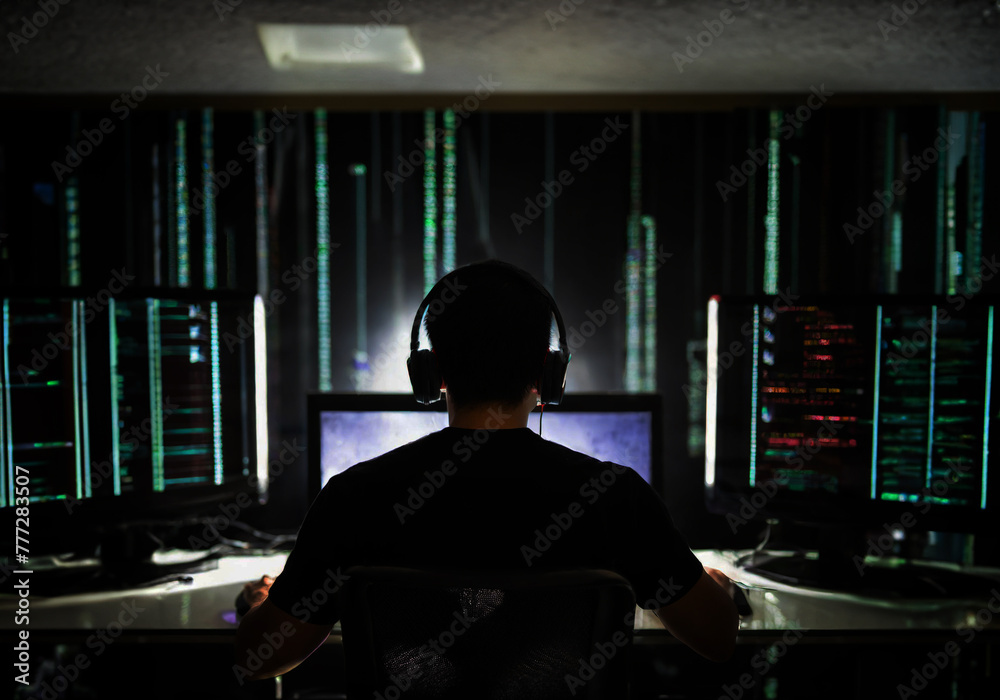 computer hacker operating computer system in a dark room computer hacker operating computer system in a dark room