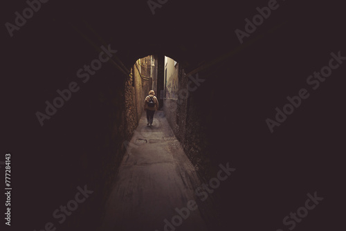 Fototapeta Naklejka Na Ścianę i Meble -  Silhouette of a woman walk in the light on the end of a dark tunnel. Woman walking the streets of Italy.