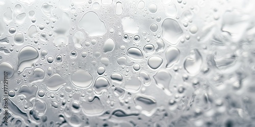 This image showcases a close-up, detailed macro shot of water droplets on a gray surface, highlighting their shapes and reflections photo