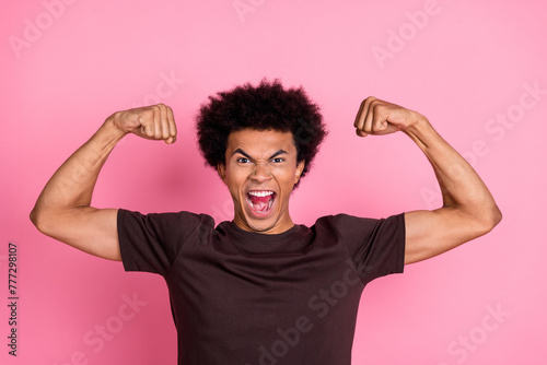 Portrait of emotional positive guy preparing for mens physique tournament competition fists up biceps isolated on pink color background