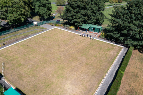 Aerial drone photo of a British Bowling green with people playing Bowls on the public park in the summer time, filmed in the city of Leeds in West Yorkshire in the UK on a sunny day in the summer.