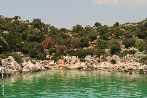 The Burc Koyu Bay, green water in the foreground and metal doorway and lush vegetation in the background, close to Demre, Turkey photo