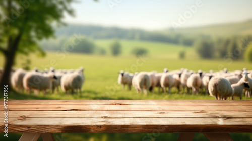 A wooden tabletop foregrounds a softly focused pastoral scene with a flock of sheep grazing in a lush green field.