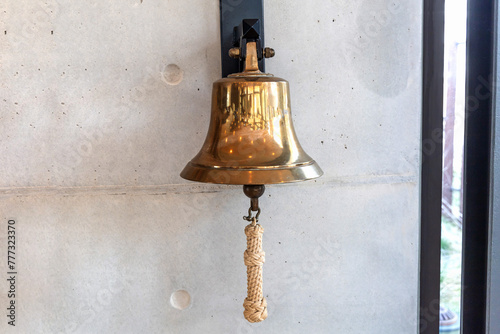 Foto Brass bell on a gray wall indoors.