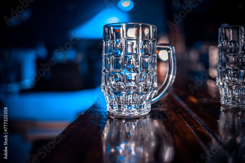 A glass mug is sitting on a wooden bar counter.