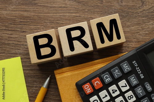 BRM - Business Reference Model bright yellow notepad and calculator near three wooden blocks with text photo