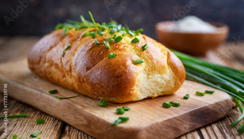 Close-up of brioche bread with chives on wooden chopping board. Fresh and tasty bakery.