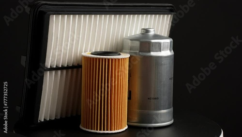 Car parts: oil filter, air filter and fuel filter rotate slowly on black background, close-up. Auto parts replacement concept, car maintenance, car service.