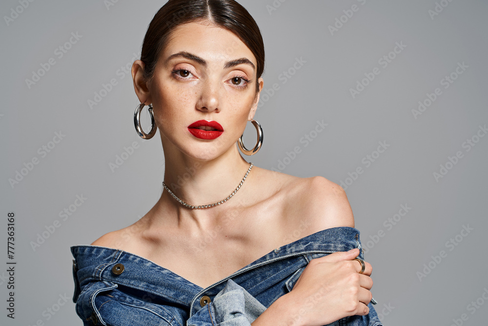 Brunette woman slaying in a denim dress, with striking red lips, exuding confidence and style in a studio setting. - obrazy, fototapety, plakaty 