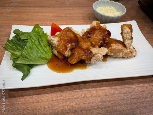 plate of chicken with black vinegar sauce on wooden table at japaness restaurant. photo