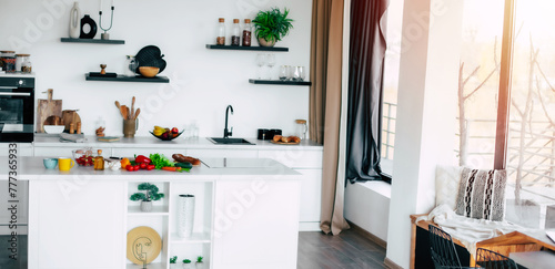 New loft apartment design with modern new light interior of kitchen with white furniture and big kitchen island. Cooking of healthy vegan salad on domestic kitchen.