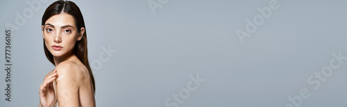 A young, clean-skinned Caucasian woman with brunette hair confidently posing with cream on shoulder, banner