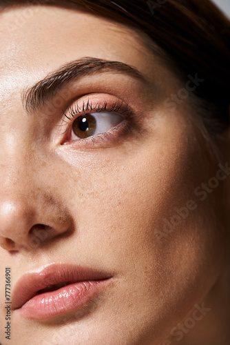 A young caucasian woman with  clean skin is featured in a close-up, highlighting her captivating brown eyes.