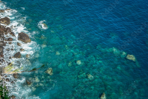 Drone view of rocks and blue pristine sea with clear transparent water. Ocean background with copy space