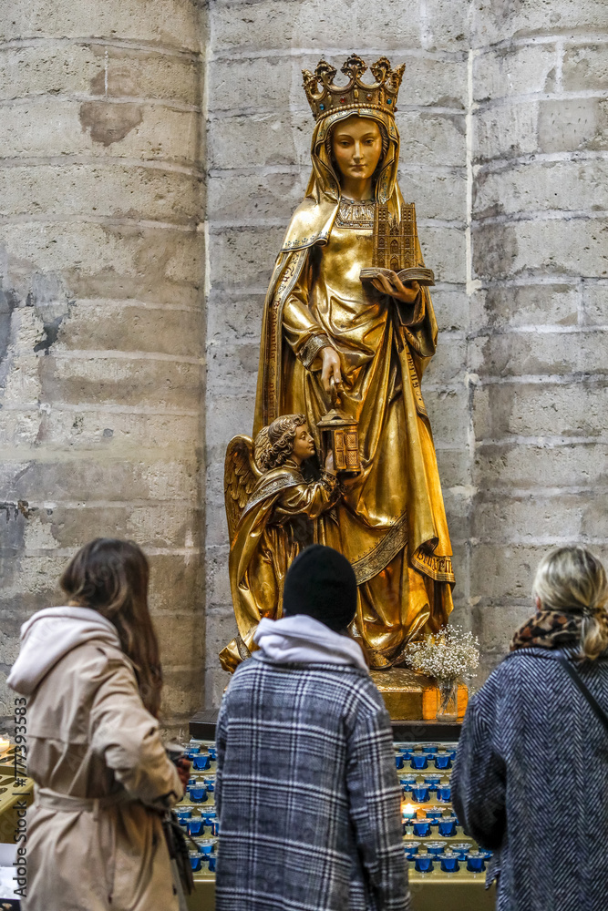 Young women in front of Sainte Gudule statue in Saints Michael & Gudule cathedral, Brussels, Belgium