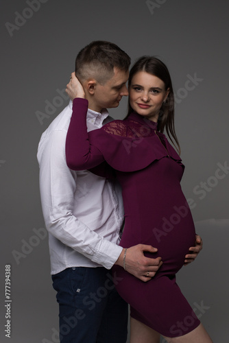pregnant couple on a grey background in a studio