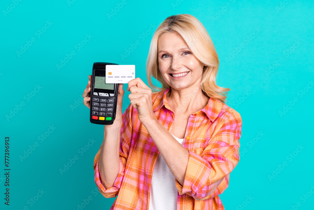 Portrait of smart woman with blond hair dressed plaid shirt make wireless paiment with credit card isolated on turquoise color background Portrait of smart woman with blond hair dressed plaid shirt make wireless paiment with credit card isolated on turquoise color background