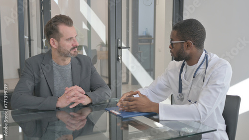 Doctor Talking with Middle Aged Man in Clinic