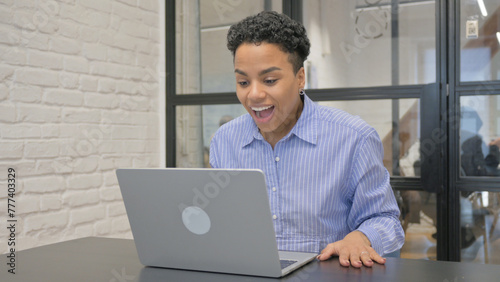 Young African Woman Celebrating Success on Laptop