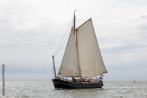 Traditional old wooden flat bottomed boat on the World Heritage Wadden Sea, the Netherlands. Calm water and blue Dutch skies, brown sails.