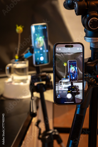 Image of telephone, phone on a tripod taking a photo of a camera phone taking a image of a still life with a flower in a studio setting