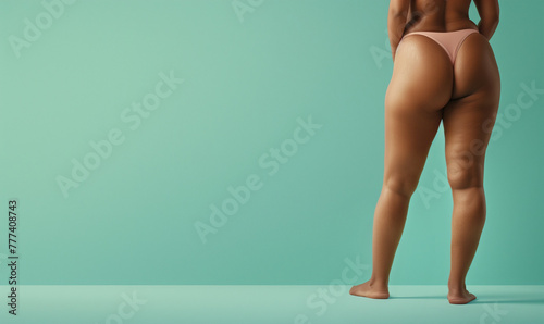 black poc woman's big butt wearing thong back view isolated on plain blue color studio background with copy text space photo