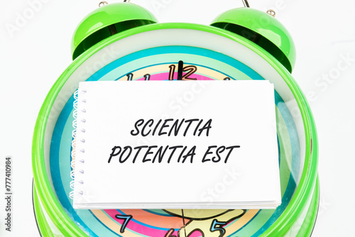 the phrase Scientia Potentia Est (Knowledge is power) written in Latin on the business card on the alarm clock photo