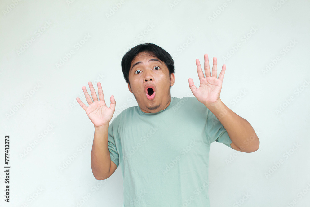 Young asian man in green t-shirt with shocked and wow expression. Isolated on gray background. Young asian man in green t-shirt with shocked and wow expression. Isolated on gray background.
