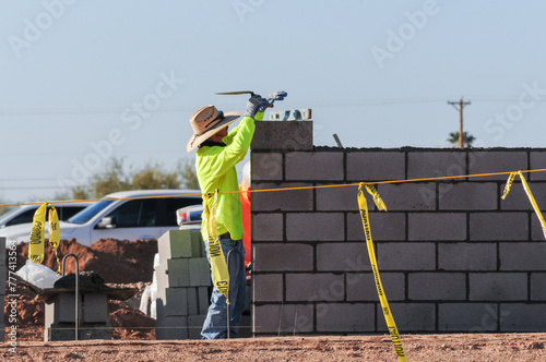 A mason worker reading a spirit level atop a block of a concrete fence he is building at a construction site in Pinal County, Arizona photo