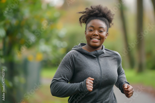 Photo of a young, happy overweight black woman running with a smile in the park, weight loss concept.