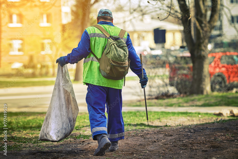 Utility worker with plastic bag and pick up tool for gathering paper, trash, plastic or metal cans. Man remove garbage with sharp stainless steel tip. Park cleanup. Garbage collection with pickup tool