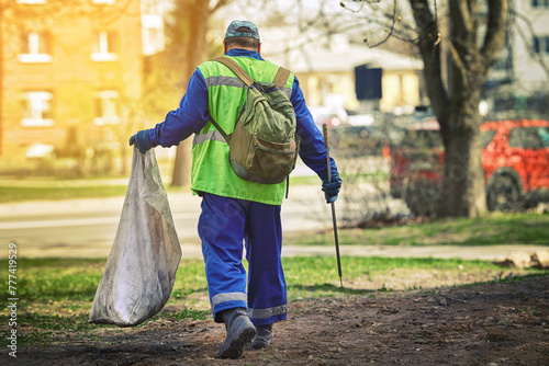 Obraz na płótnie Utility worker with plastic bag and pick up tool for gathering paper, trash, plastic or metal cans. Man remove garbage with sharp stainless steel tip. Park cleanup. Garbage collection with pickup tool w salonie