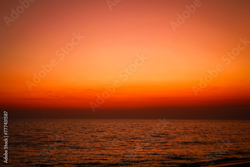 Fototapeta Naklejka Na Ścianę i Meble -  The sea after sunset has an orange glow and an orange sky with no clouds.