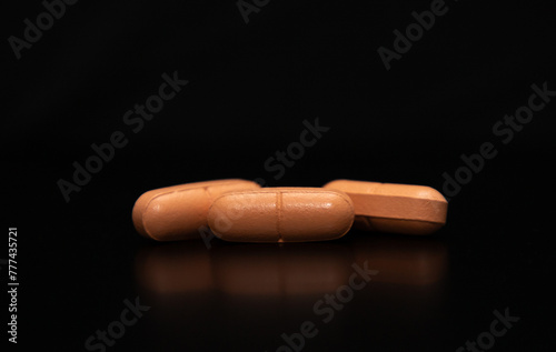 A close up with a group of three pills on a black background, perfect for ornamental or decorative image